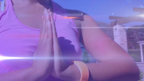 animation of light spots over biracial woman practicing yoga and meditating