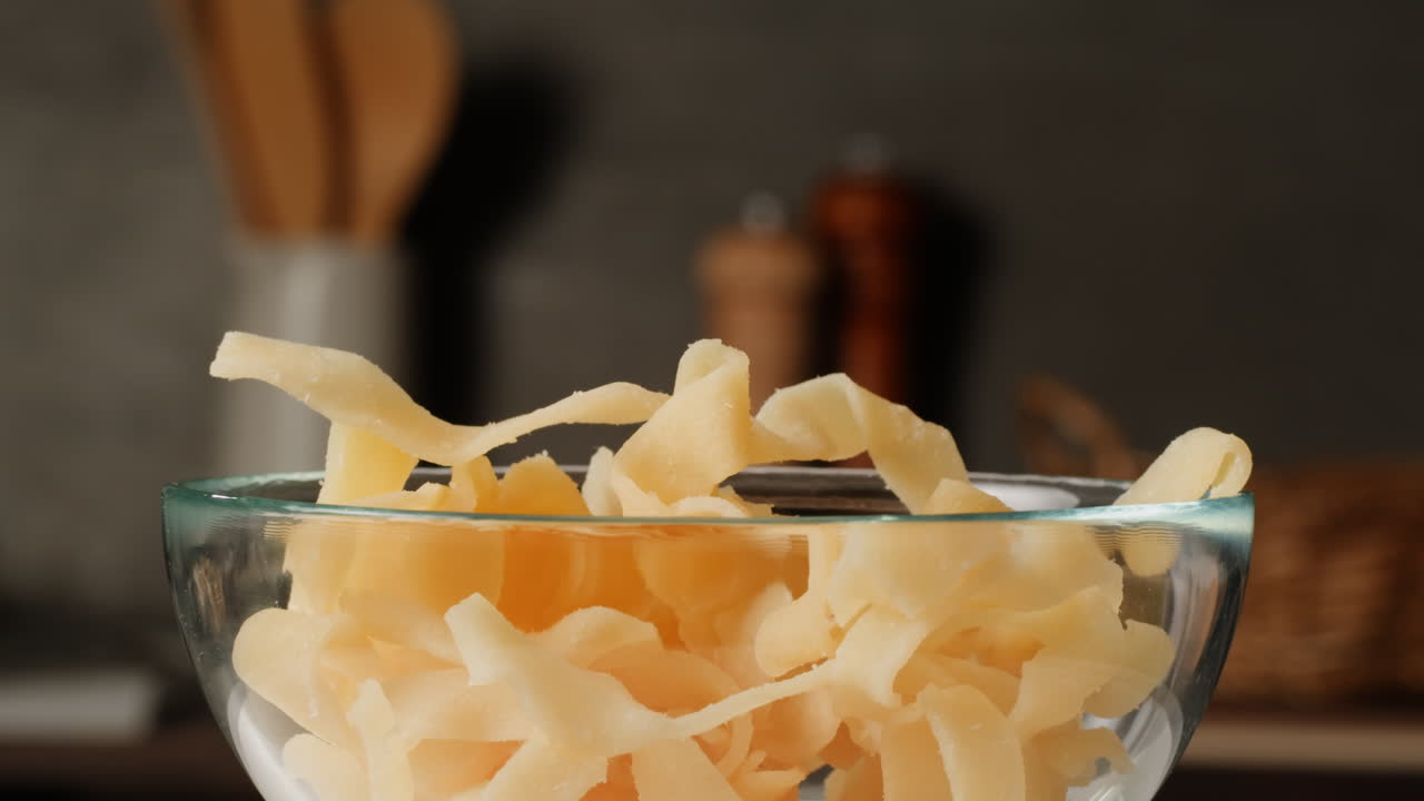 Hand picking dried noodles from a glass bowl