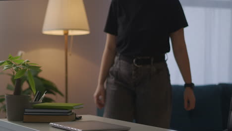 mujer está encendiendo la luz de la lámpara de piso sentada en la mesa para navegar por internet con una computadora portátil trabajando remotamente en casa mujer joven con un cuaderno en la sala de estar