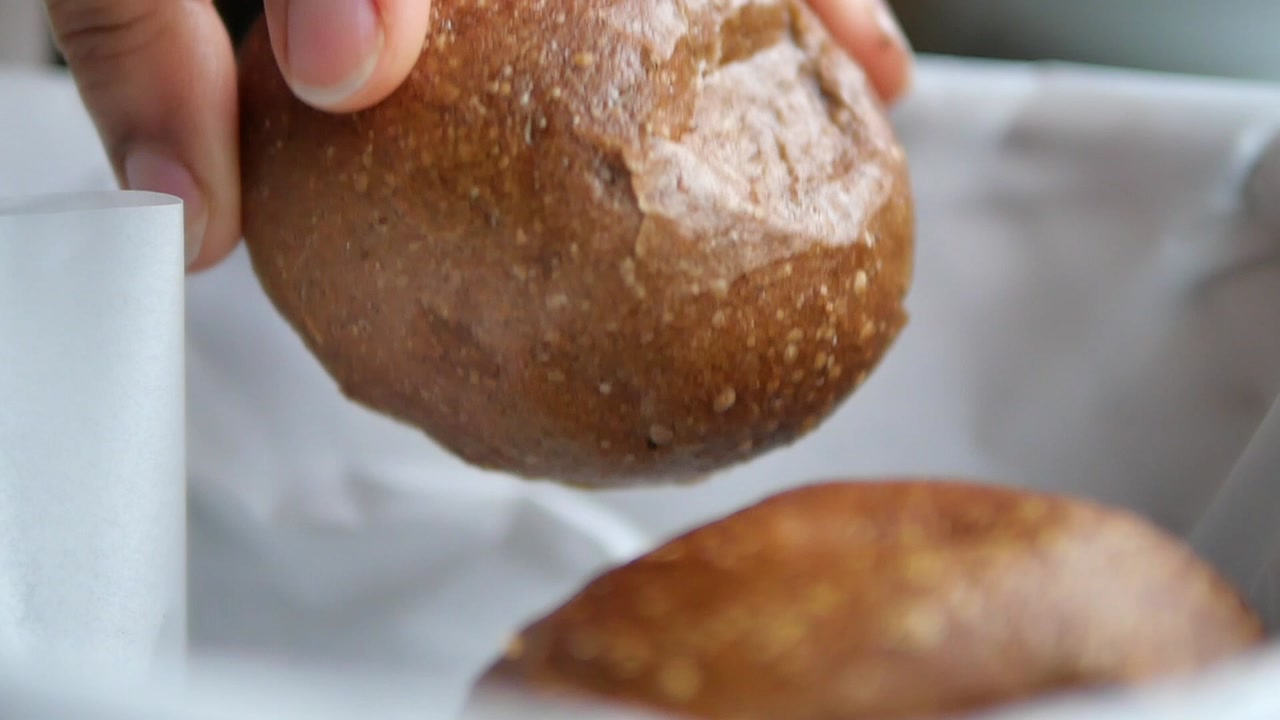 Close-up of Hand Picking Up a Fresh Bread Roll