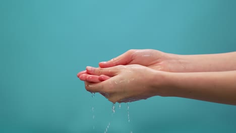 splash of clean water flows into the hands on the blue background. the concept of saving water to make it last for a long time.