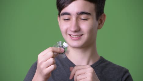 young handsome iranian teenage boy against green background