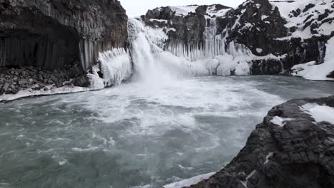 Scenic-waterfall-streaming-from-rocky-cliff-on-winter-day