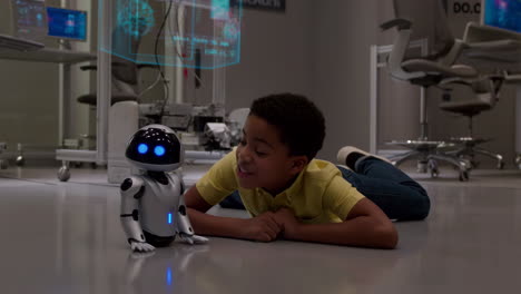 a young boy interacts with a small robot in a futuristic laboratory setting
