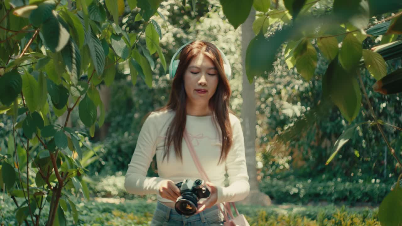 movimiento lento de un joven artista tomando una foto en un parque natural al aire libre mientras escucha música con auriculares