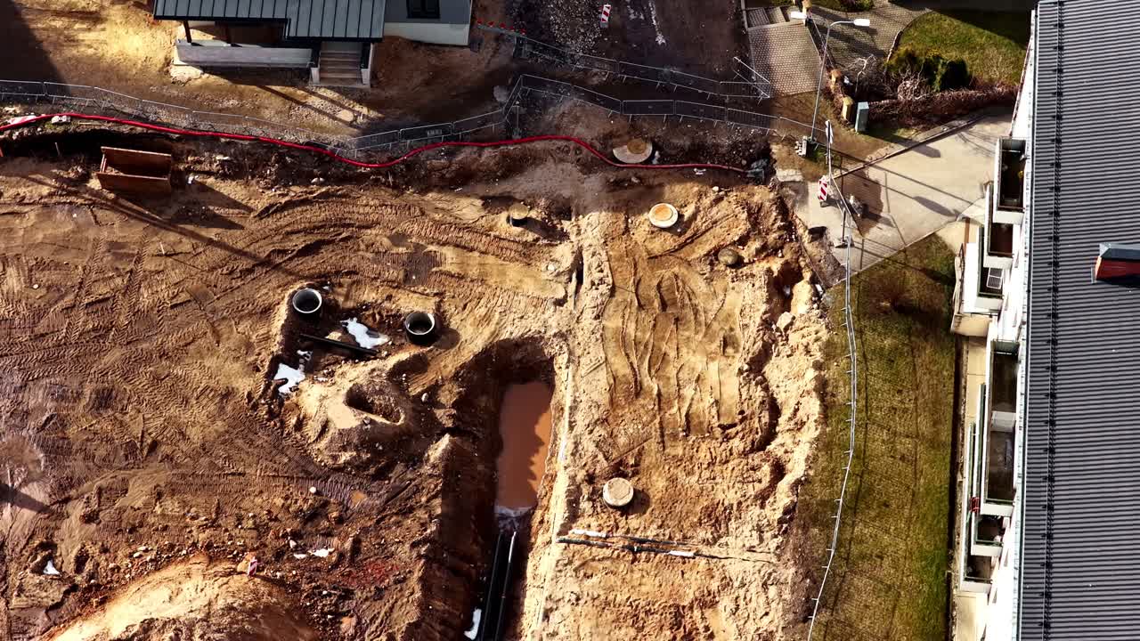 Excavation site preparing for pipelines and foundation alongside residential homes