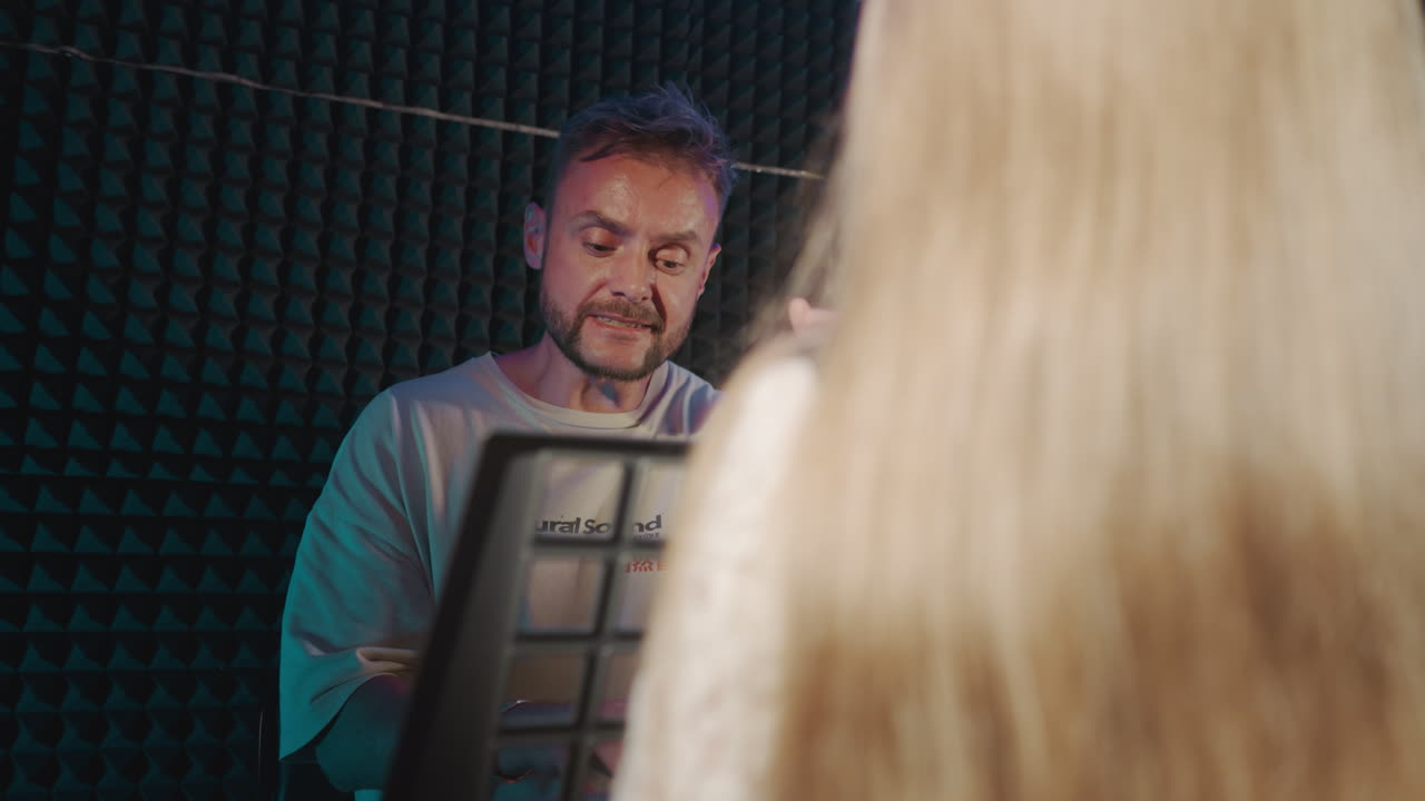 el padre apoya el canto del niño en la escuela. el instructor vocal canta junto con la estudiante durante la sesión vocal. el niño dotado en el estudio de grabación de audio