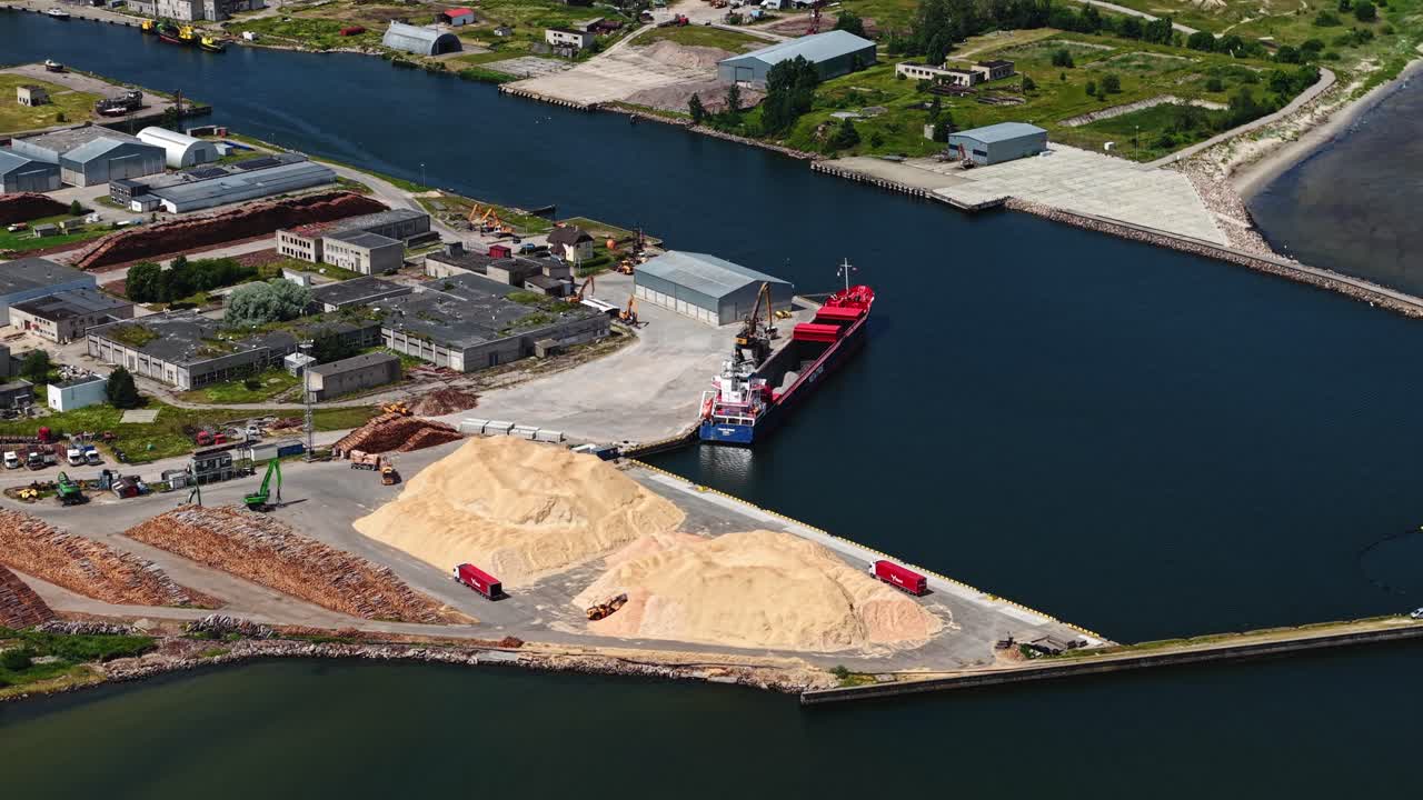 Top-down shot of shipping operations with a red ship and bulk material handling