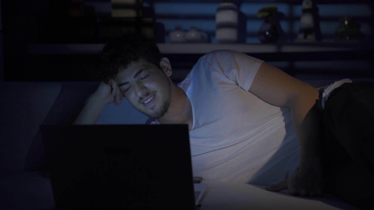 Cheerful man working on laptop at home, looking.