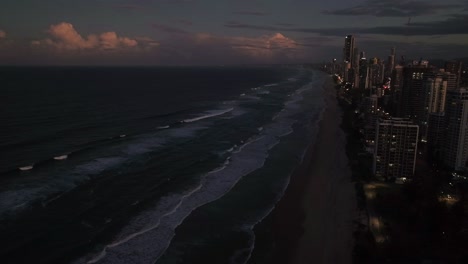 Paraíso-De-Los-Surfistas,-Costa-Dorada,-Queensland,-Australia,-Drone,-Las-Luces-Se-Encienden-Mientras-Se-Pone-El-Sol-En-Este-Famoso-Destino-Vacacional