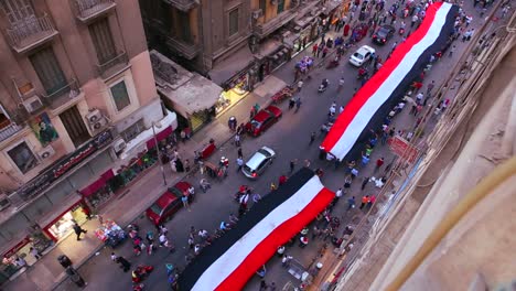 view from overhead looking straight down as protestors carrying banners march in the streets of cairo egypt