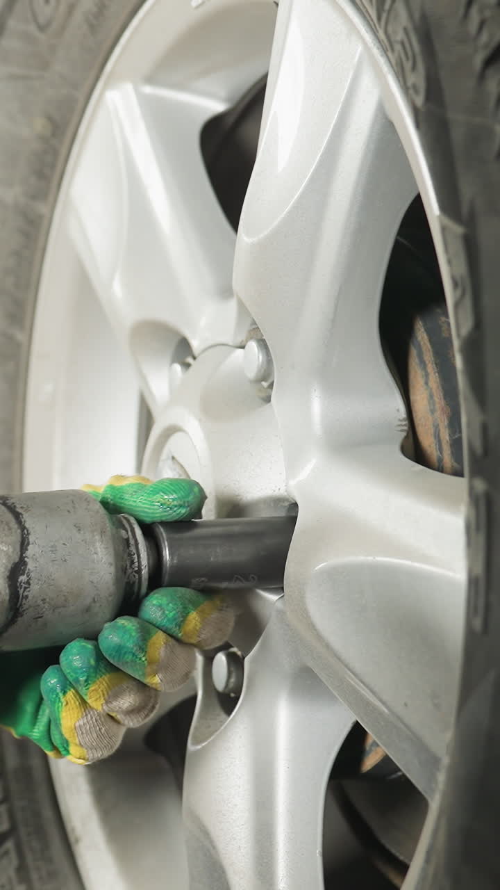 vista de cerca de un ingeniero observando atentamente a un colega usando una herramienta neumática para apretar el perno de un automóvil en un garaje, centrarse en la precisión y el mantenimiento profesional de automóviles