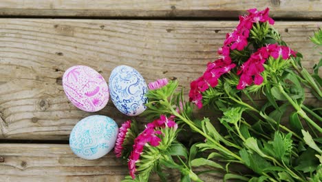 painted easter eggs and bunch of flower on wooden background