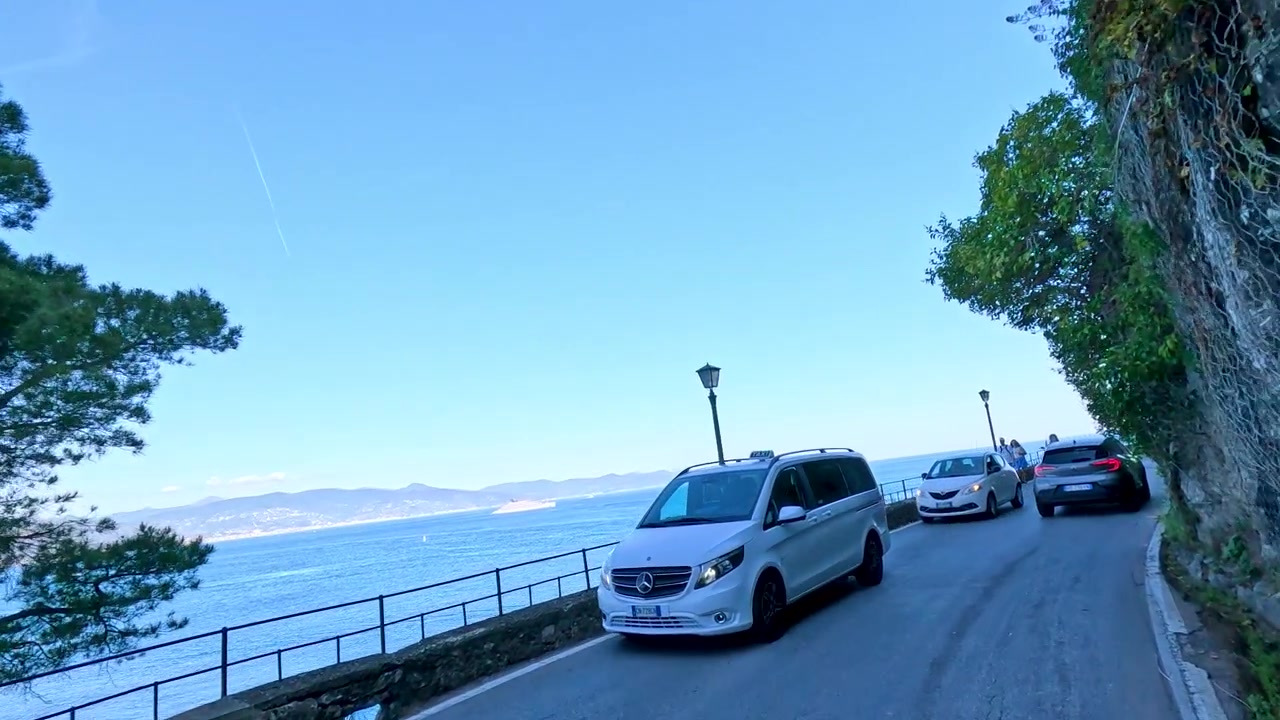 ポルトフィーノで、地中海を見下ろす狭く曲がりくねった崖沿いの道を走行する車両。