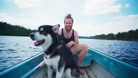 caucasian guy boating with his alaskan malamute. pov