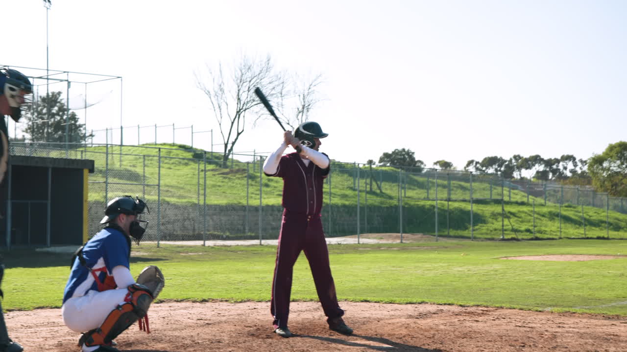 Playing baseball, batter in helmet and uniform preparing to hit pitch