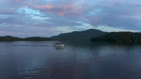 Drone-Volando-Frente-A-Un-Bote-Solitario-Al-Atardecer-En-Un-Lago-Con-Un-Cielo-Colorido-En-El-Municipio-Del-Este,-Quebec,-Canadá