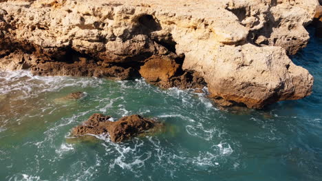 Aerial-view-showing-moving-waves-at-rocky-coastline-of-Portugal-during-sunny-day