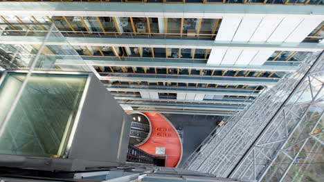 Vídeo-Desde-El-Interior-Del-Stadttor-De-Düsseldorf,-Filmado-Desde-Arriba-Que-Captura-Un-Ascensor-Que-Asciende-En-Medio-De-Un-Vasto-Escenario-De-Cristal,-Ofreciendo-Una-Vista-Total-De-La-Elegancia-Arquitectónica.