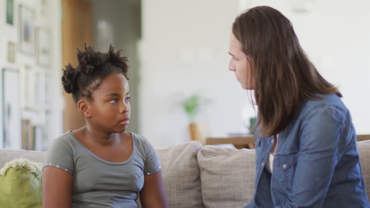Caucasian woman embracing her african american daughter in living room
