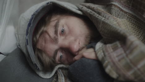person sleeping comfortably under a patterned blanket with a hoodie