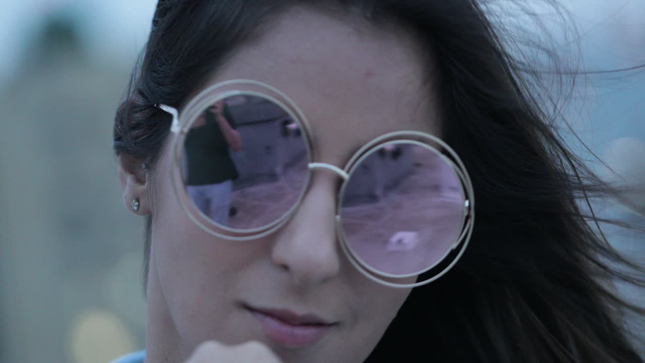 chica posando con gafas de sol grandes y redondas por la noche