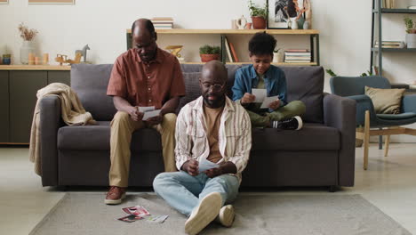 hombres negros y un niño mirando fotografías en la sala de estar.