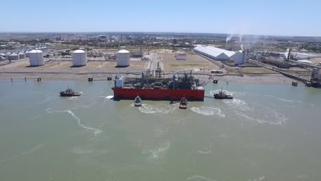 aerial view of cargo ship arriving at the port with the help of tugs