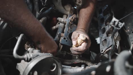 Primer-Plano-De-Manos-Trabajando-Con-Herramientas-Manuales-En-Un-Motor-Sucio-Aceitoso,-Dentro-Del-Taller