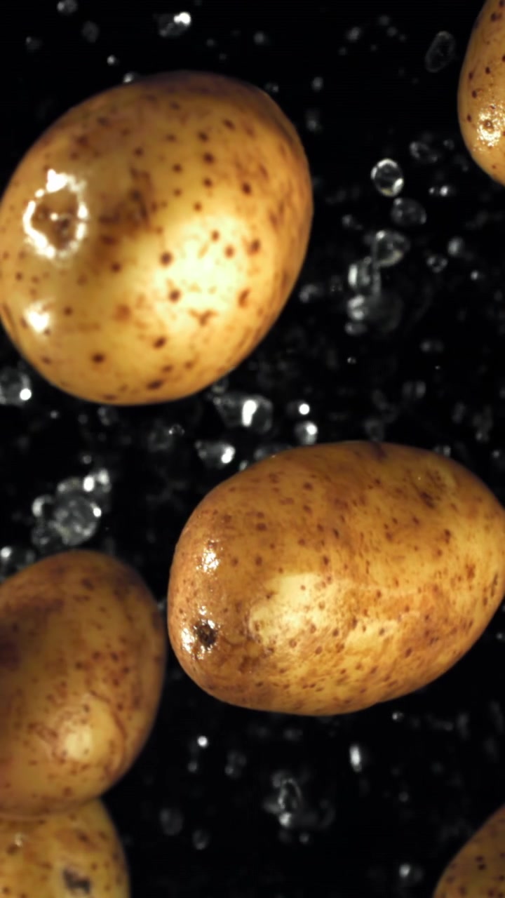 Patate fresche che cadono al rallentatore con gocce d'acqua