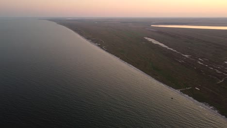 High-altitude-shot-of-the-idillyc-coastline-of-wild-beaches-of-Vadu,-Romania,-where-the-Black-Sea-meets-the-natural-green-ecosystem