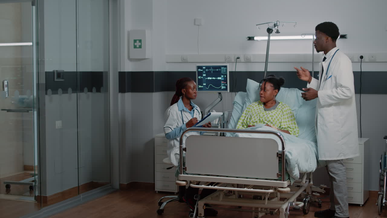 Medical team talking to sick woman in hospital ward bed
