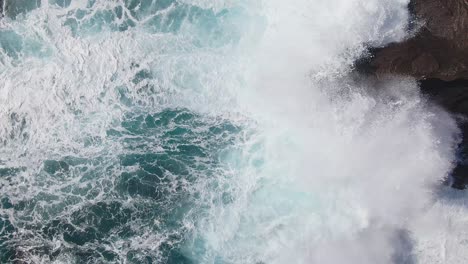 Overhead-view-of-waves-crashing-onto-rocky-coast-off-of-Kahauloa-Cove