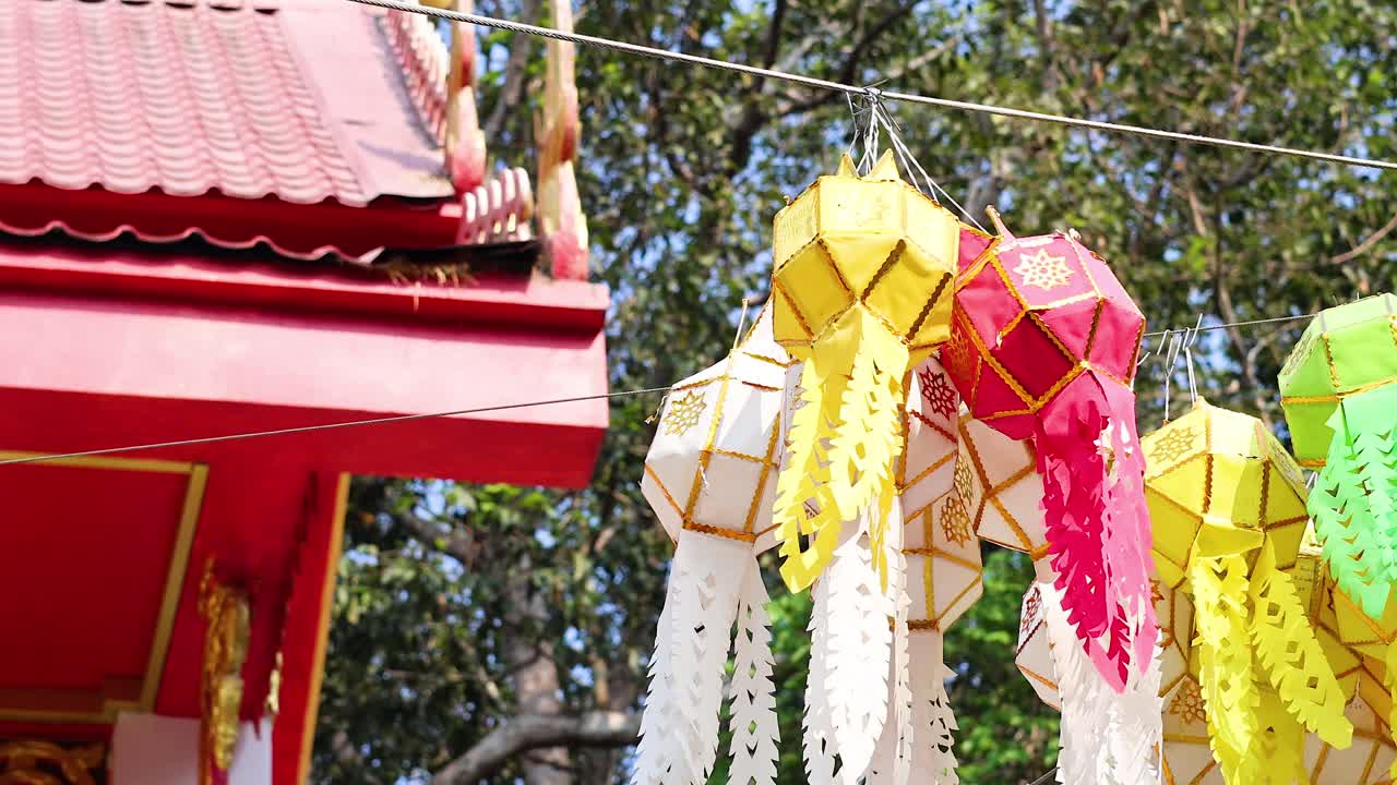 โคมไฟสีสันสดใสแขวนอยู่ใต้ชายคาวัดในเวลากลางวัน