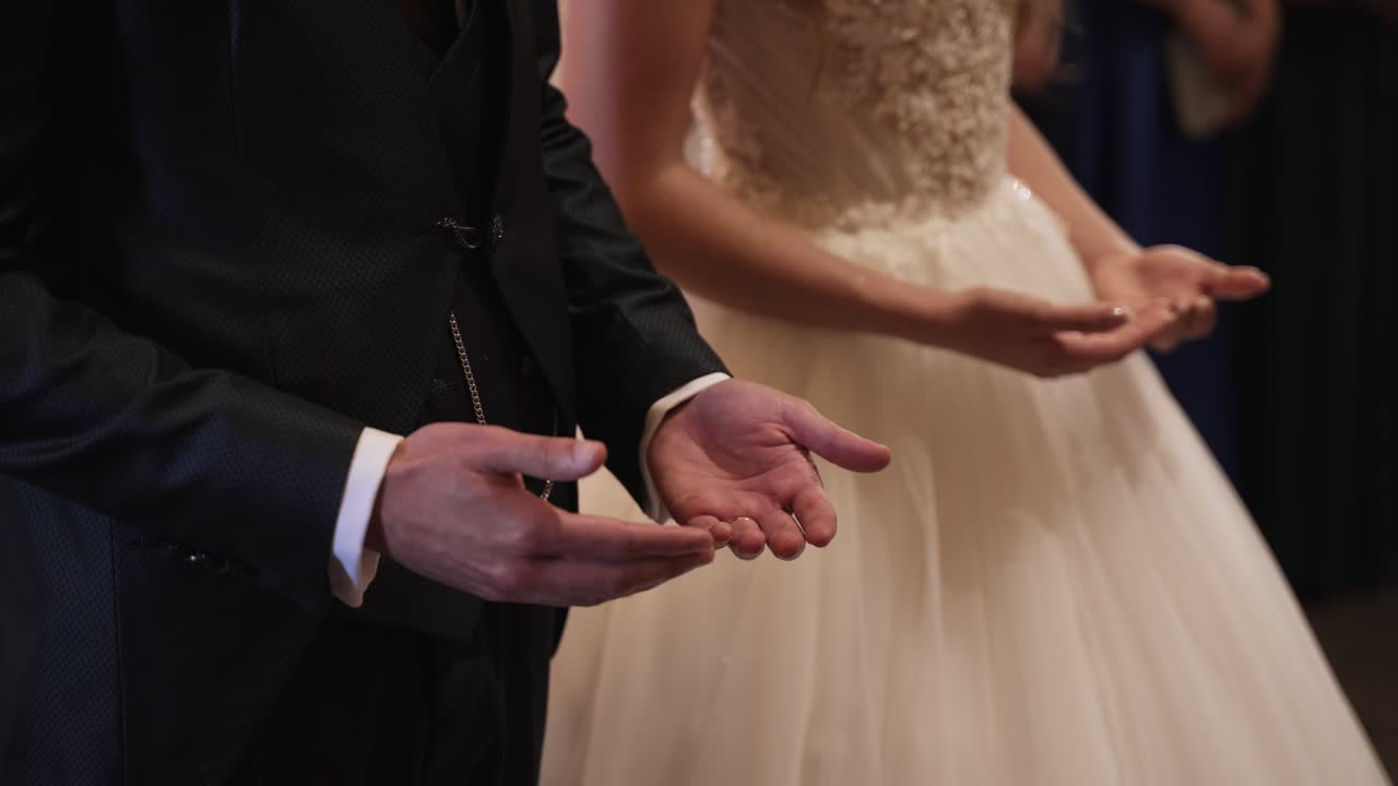 Bride and groom with open hands in a solemn wedding ceremony moment indoors