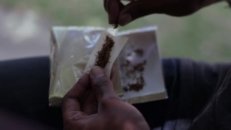 Una-Toma-A-Cámara-Lenta-Oh-Manos-Masculinas-Preparando-Tabaco-Para-Convertirlo-En-Un-Cigarrillo