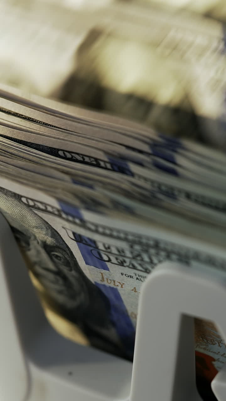 Rotating mechanism of cash machine turning money. One hundred dollar bills being counted in electronic device. Close up. Vertical video