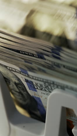 rotating mechanism of cash machine turning money. one hundred dollar bills being counted in electronic device. close up. vertical video