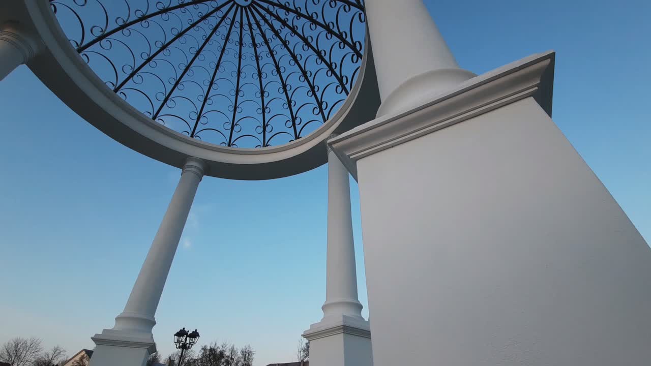 White Gazebo with Ornate Metal Dome under a Blue Sky