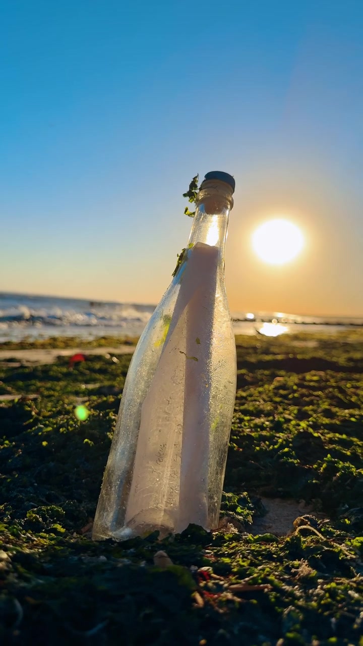 Messaggio in bottiglia sulla spiaggia. Una bottiglia di vetro con un messaggio scritto a mano si trova sulla spiaggia al tramonto, simboleggiando speranza, segreti e narrazione emotiva