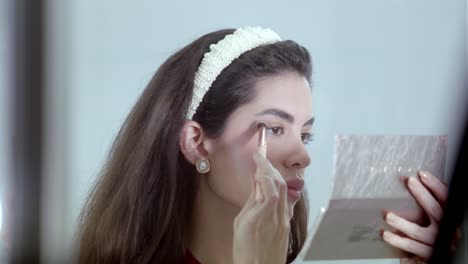 woman applying eyeshadow carefully selects shade from her eyeshadow palette