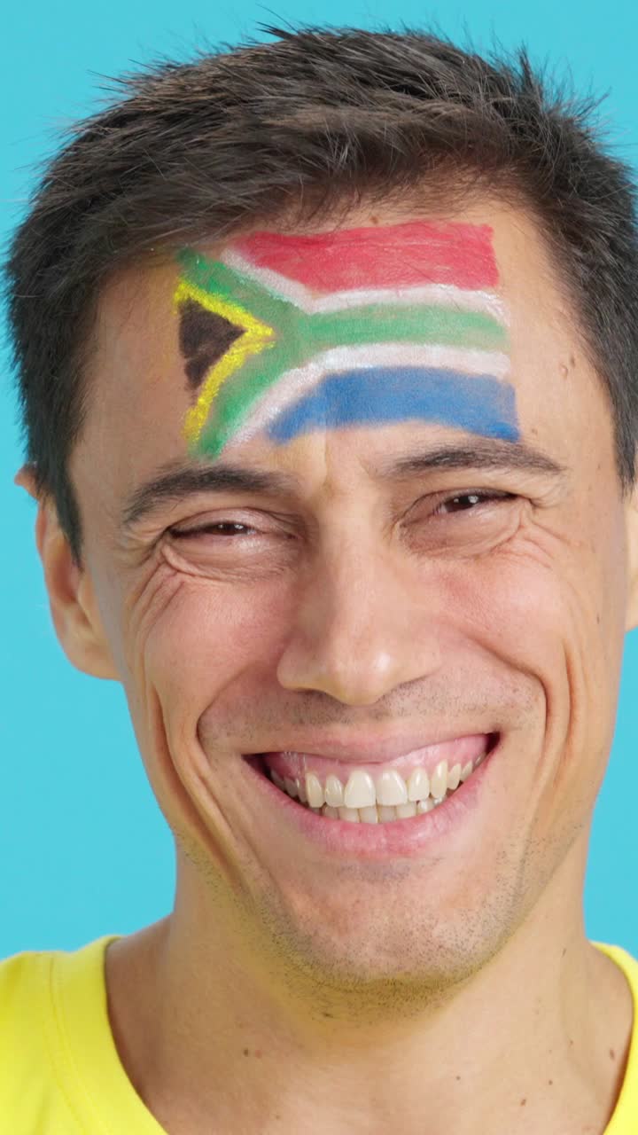 Man with a south african flag painted on the face smiling