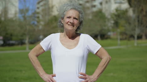 Smiling-senior-woman-posing-on-green-meadow.