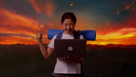 mujer feliz celebrando el éxito en la cima de una montaña con una computadora portátil