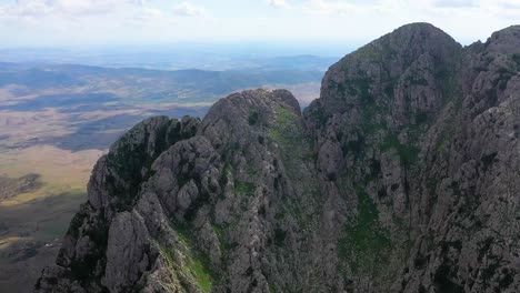 Luftaufnahme,-Die-über-Den-Rand-Der-Klippe-Von-Zaghouan-In-Tunesien-Fliegt,-Mit-Einer-Epischen-Und-Dramatischen-Landschaft-Aus-Feldern-Und-Ebenen-Dahinter