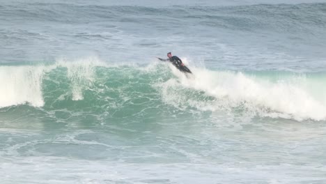 persona está haciendo surf en el mar de sagres, tiene algunas de las mejores olas de surf en portugal, con olas masivas y poderosas que ruedan sin obstáculos desde el océano atlántico