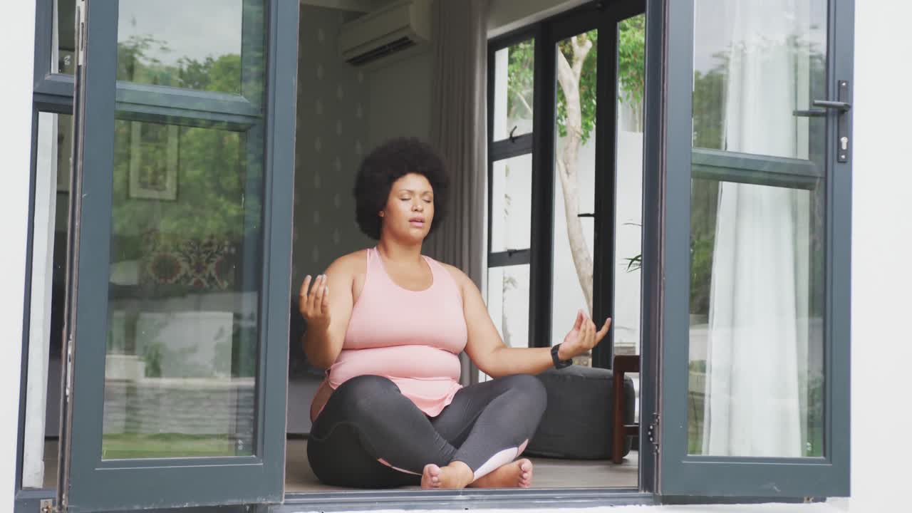 video de una mujer afroamericana de talla grande haciendo ejercicio en casa, practicando yoga