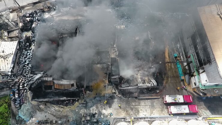 Aerial view overlooking firefighters extinguishing a house on fire, sunny day, in Port-Au-Prince, Haiti - tracking, drone shot