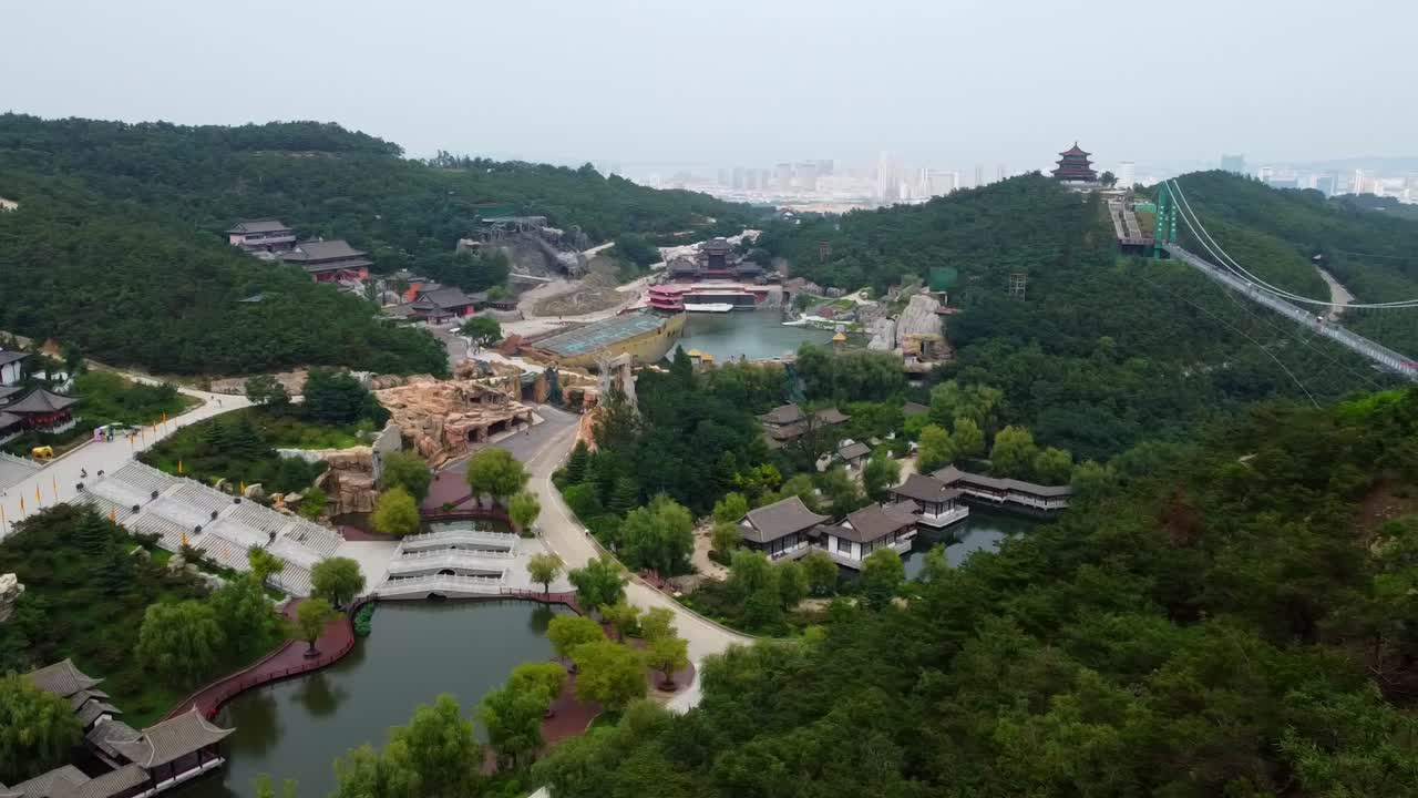 vista aérea dinámica izquierda del puente de vidrio huaxiacheng y el parque acuático en weihai, china
