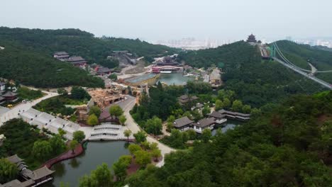 dynamic aerial left pan view of huaxiacheng glass bridge and water park in weihai, china